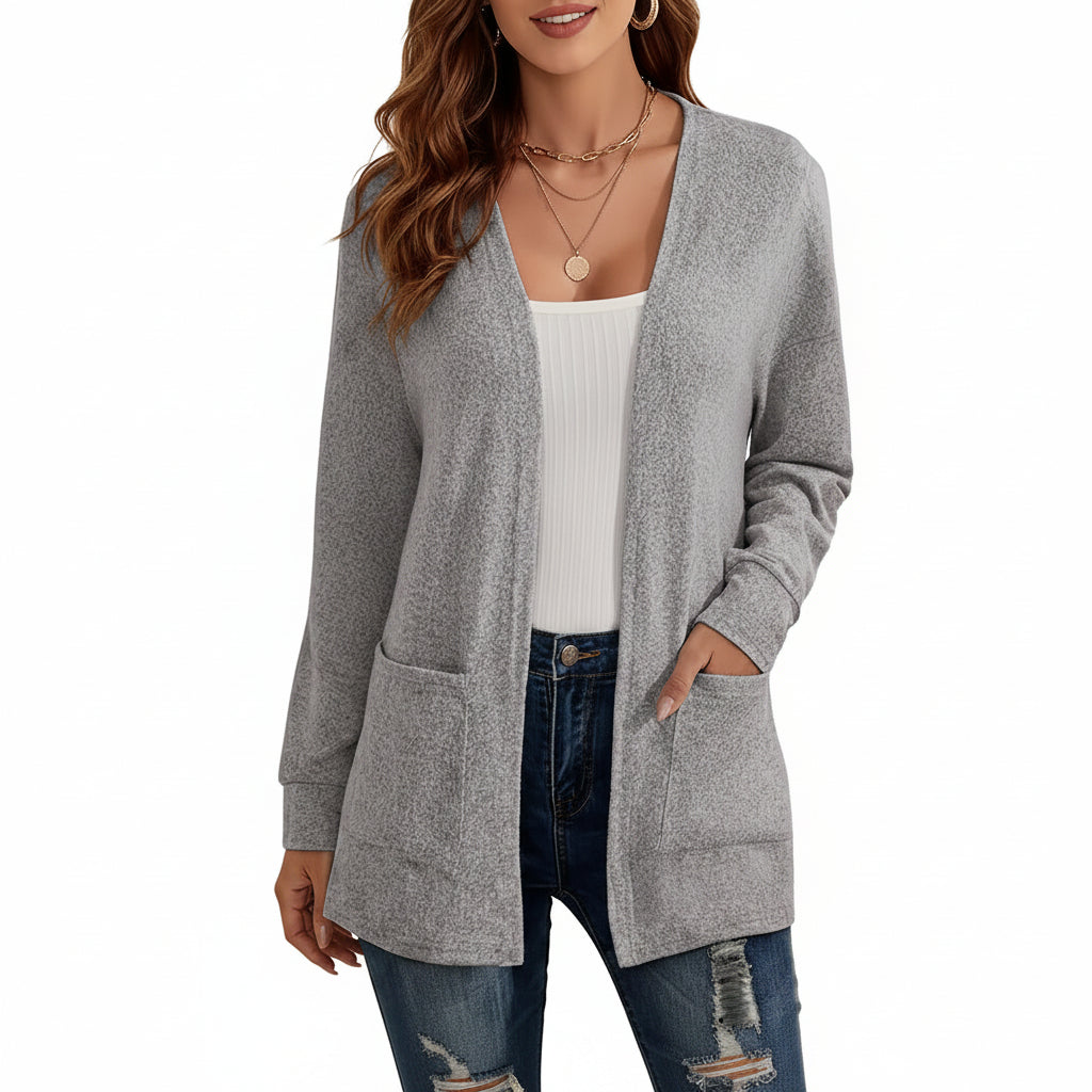 Woman wearing a gray cardigan over a white top and blue jeans with a blurred background