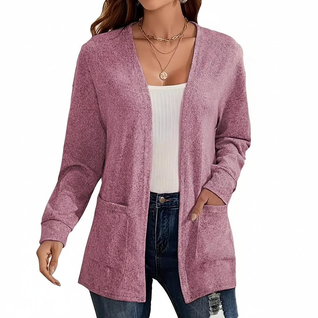 Person wearing a pink cardigan over a white top and blue jeans, with a blurred background.