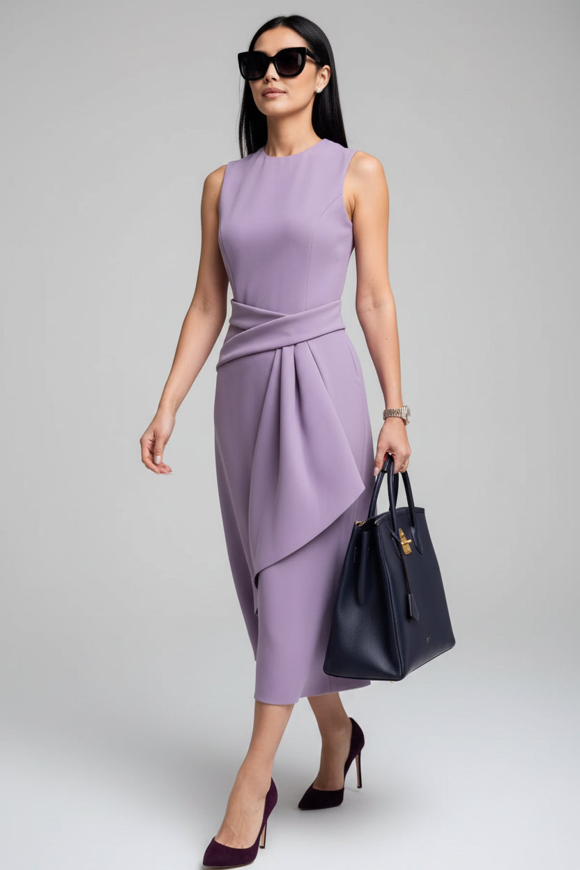 Woman in a purple dress holding a black handbag against a dark wall.