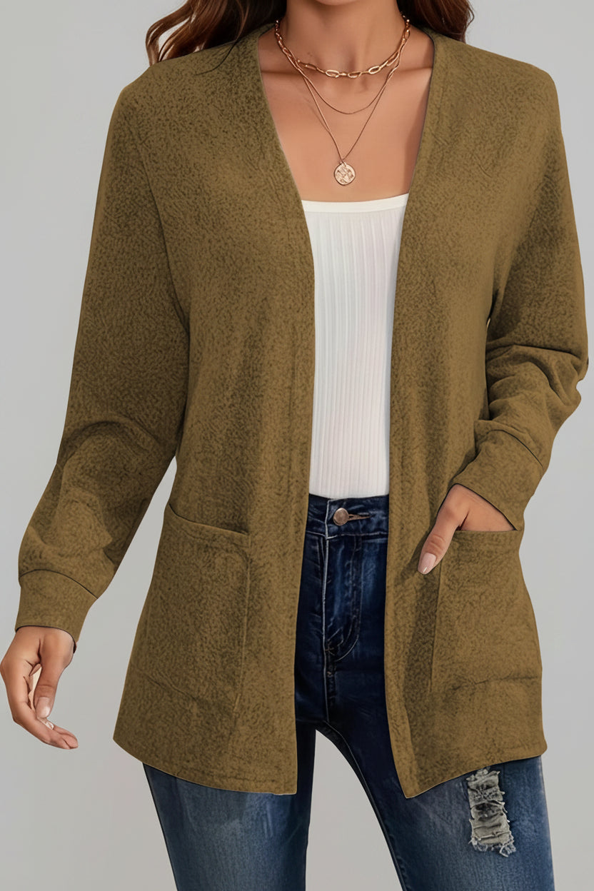 Person wearing a green cardigan over a white top and blue jeans with a blurred background