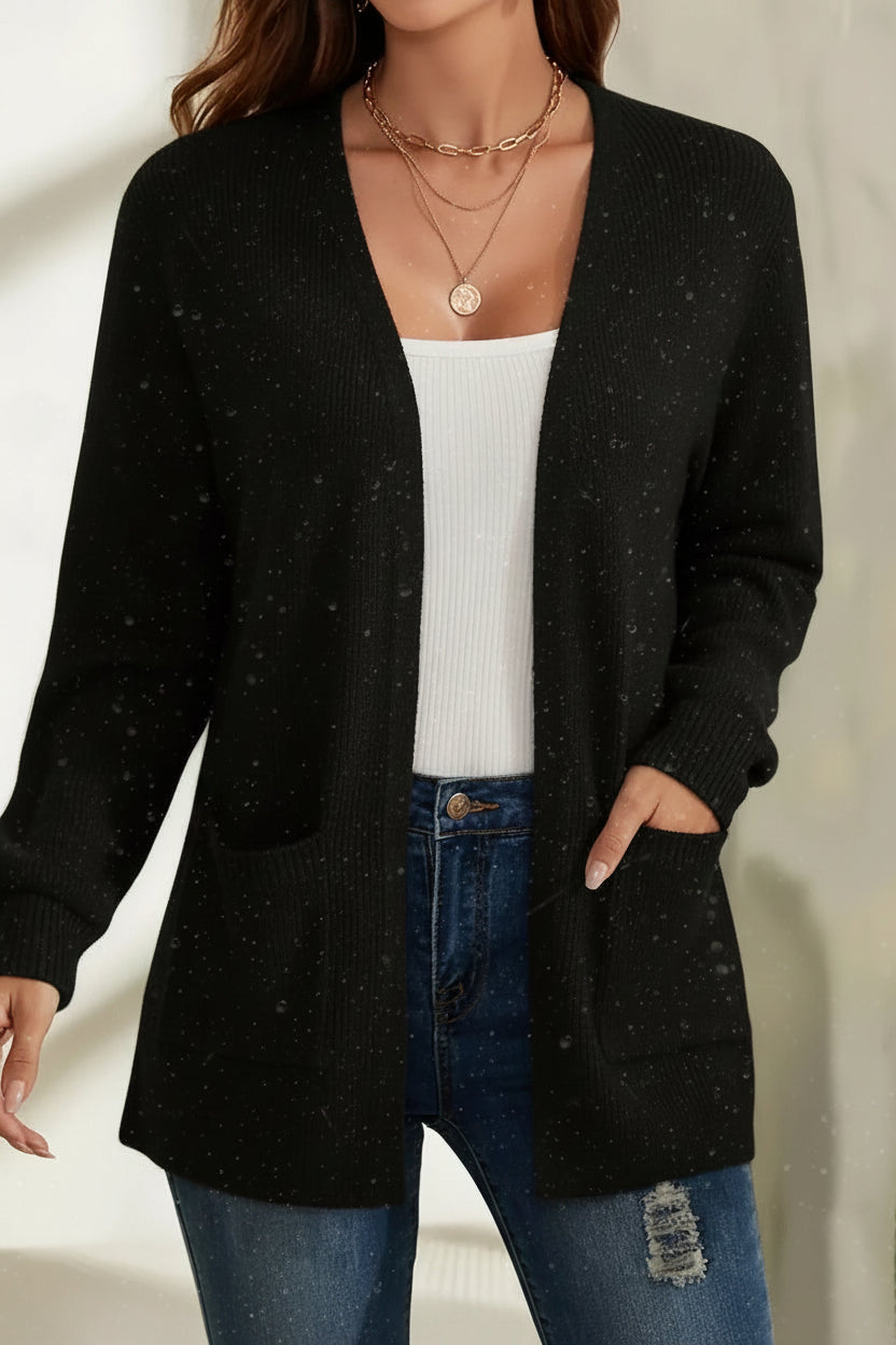 Person wearing a black cardigan over a white top and blue jeans on a neutral background