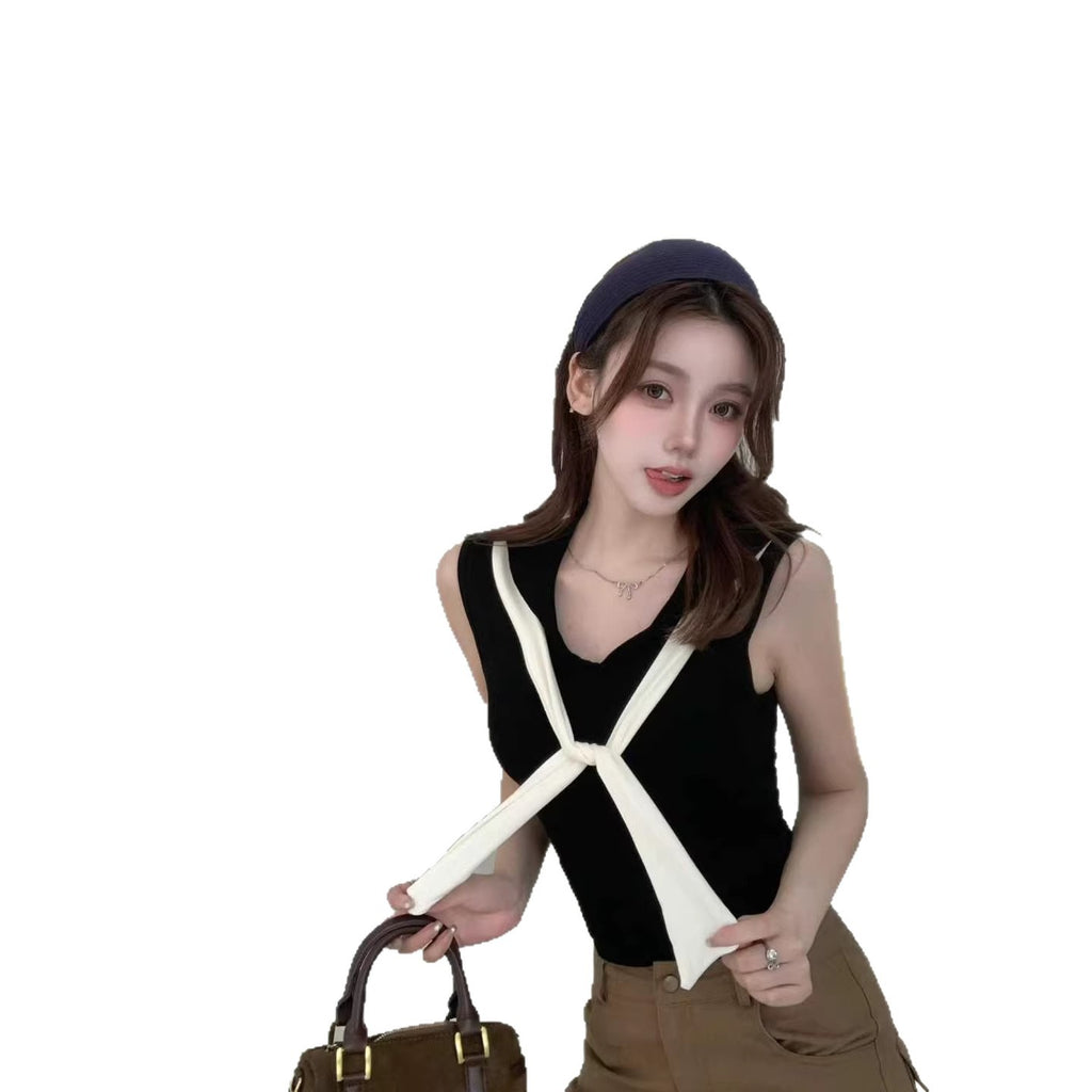 Woman wearing a black sleeveless top with white straps, holding a brown handbag on a white background