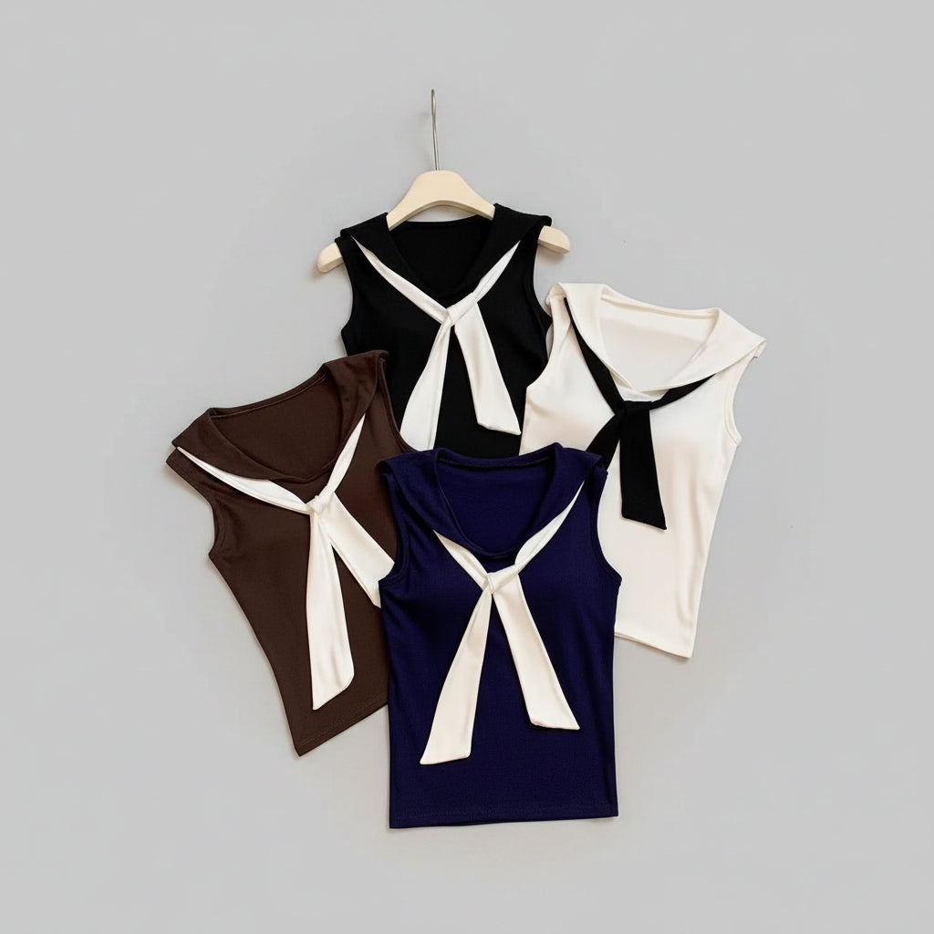 Four sleeveless tops with bow details on a textured surface with shoes and a teddy bear in the background.
