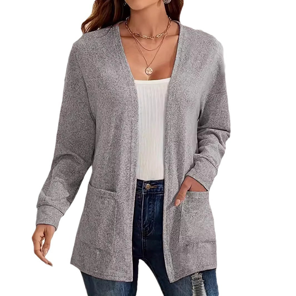 Woman wearing a gray cardigan over a white top and blue jeans on a white background